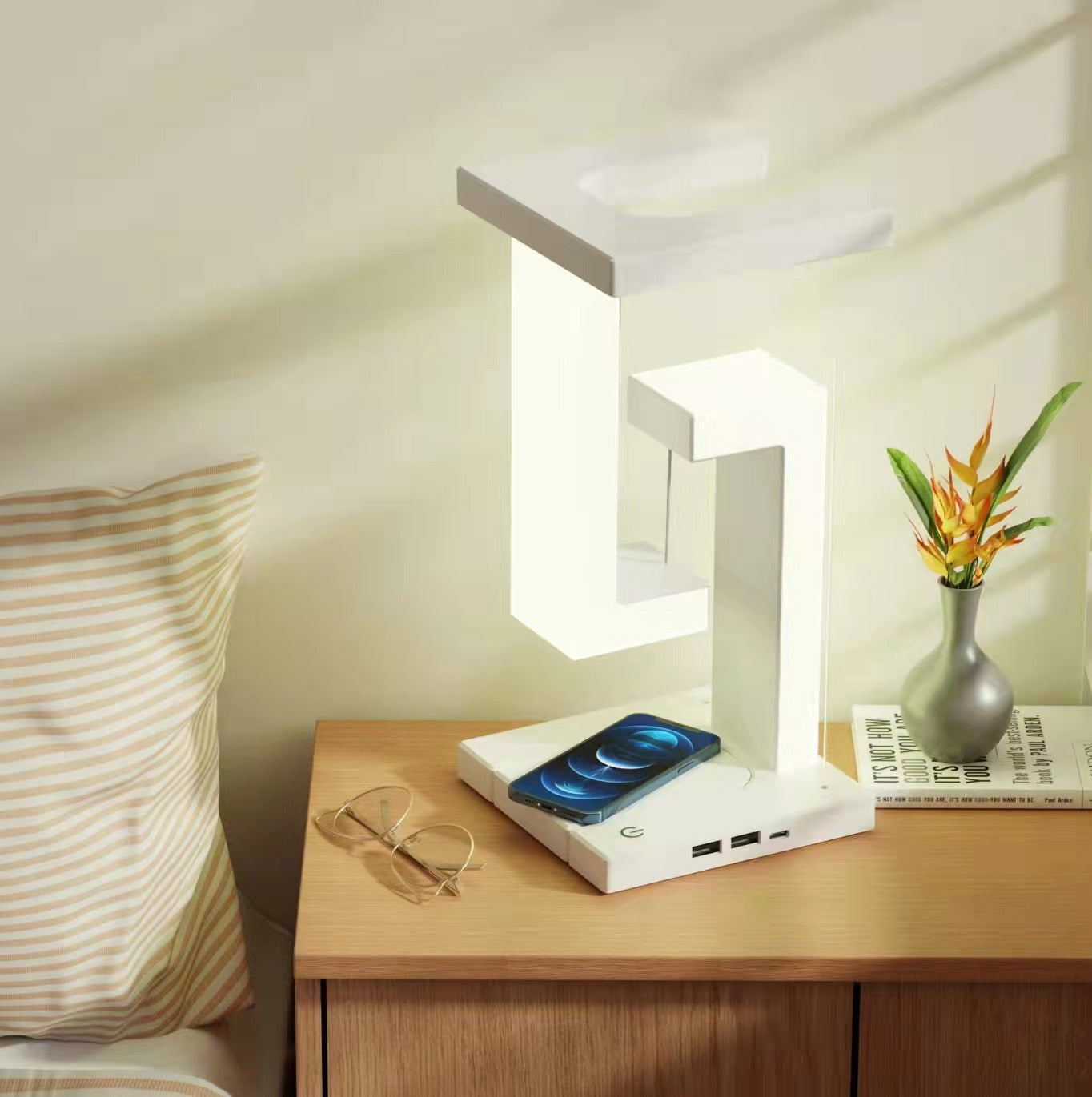 Modern table lamp on a bedside table with a smartphone and glasses.
